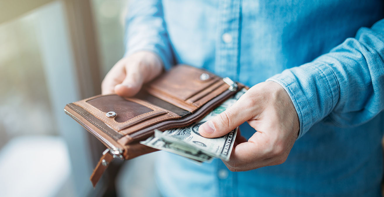Person pulling a few dollars out of a wallet