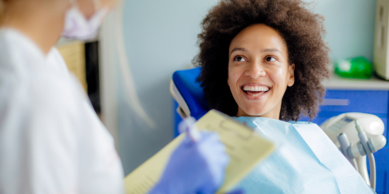 Black woman sitting in a dentists chair smiling